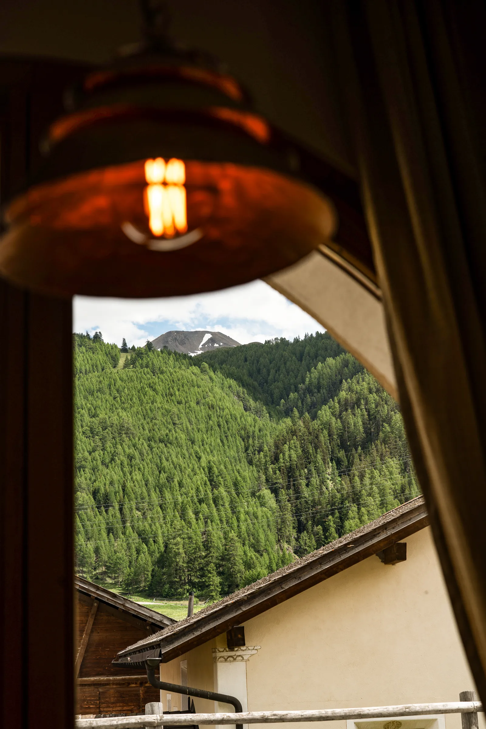 Lampe und Bogenfenster mit Blick auf den Lärchenwald